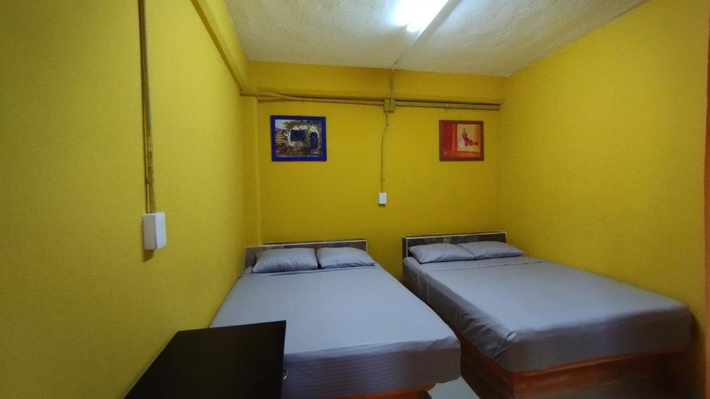 ComalcalcoNovHotel的黄色墙壁客房的两张床