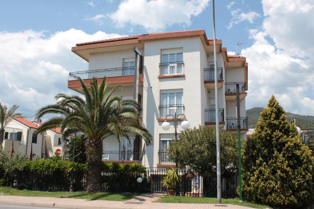 洛阿诺Residence Colibrì Family & Bike的一座白色的建筑,前面有棕榈树