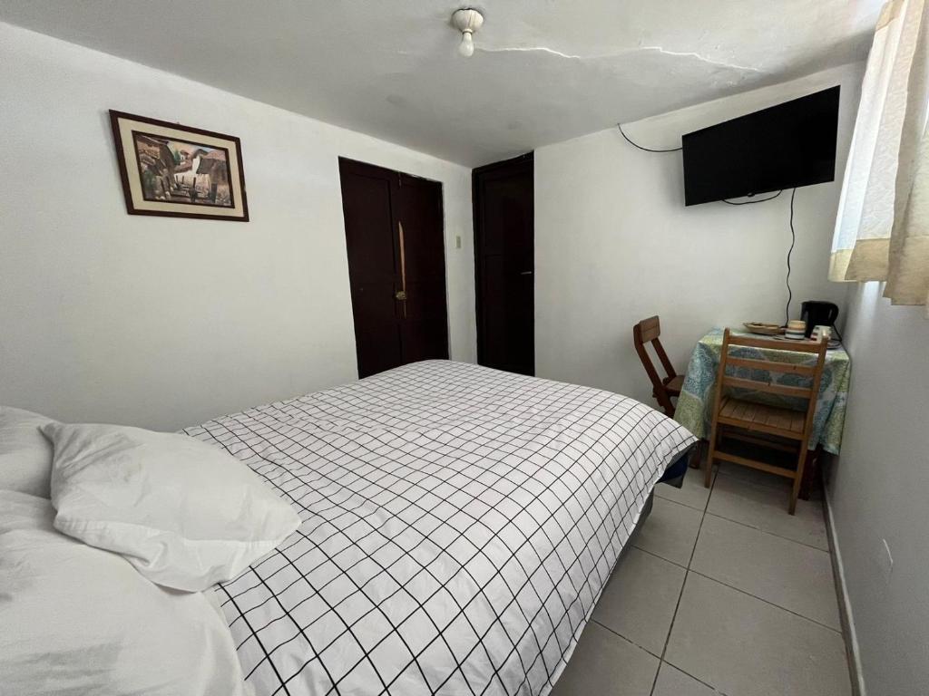 库斯科Qosqollay Plaza de armas的一间卧室配有一张床、一张桌子和一台电视