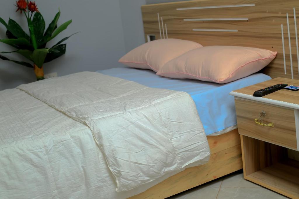 BulengaEQUATOR GATES HOTEL的一张带两个枕头和木制床头板的床
