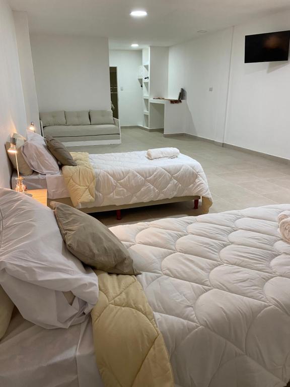 圣米格尔·德·图库玛GMP Suites的带三张床和一张沙发的房间
