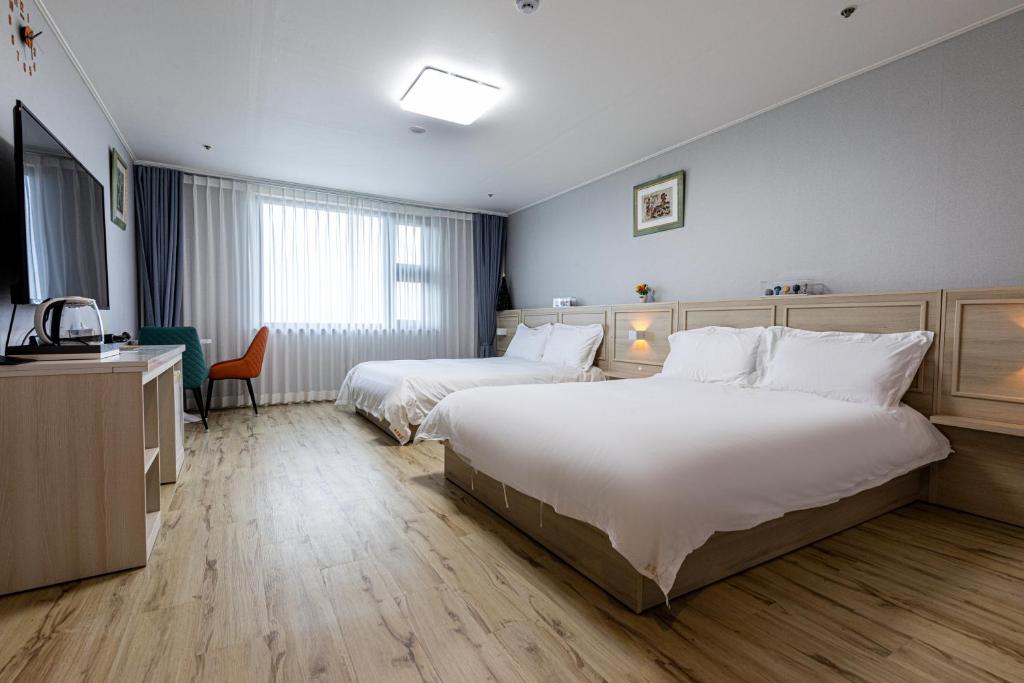 济州市New Korea Resort的酒店客房设有两张床和电视。