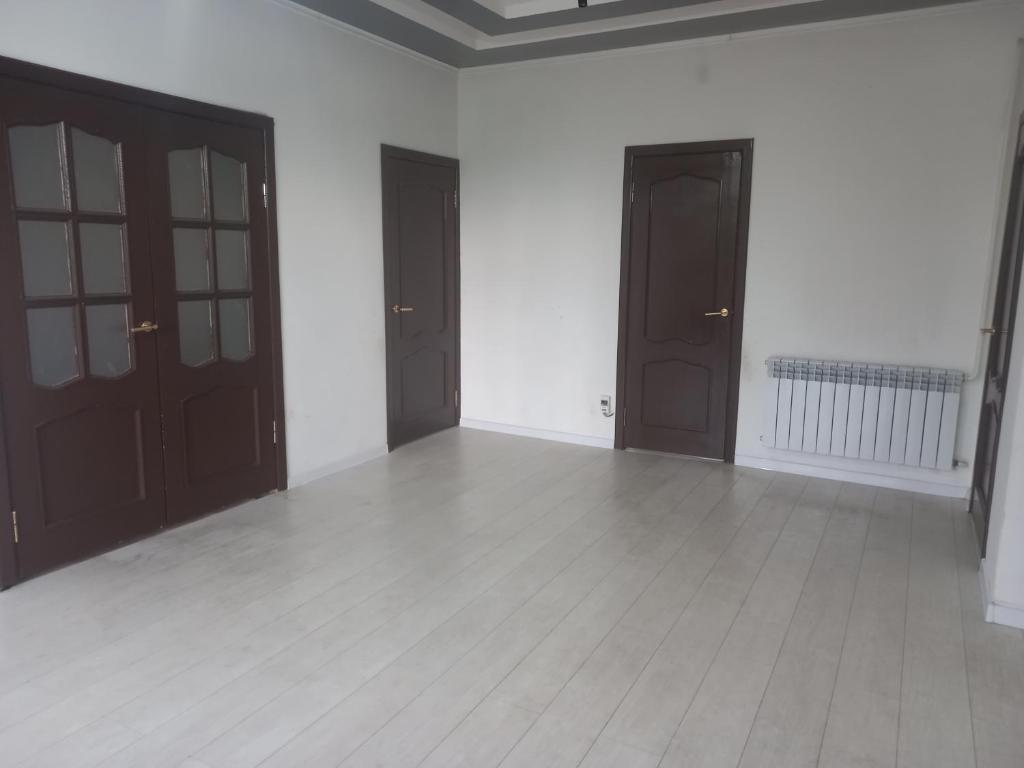 KerbenZholaman的一间空房间,设有棕色的门和白色的墙壁
