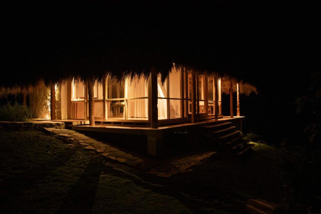 Patiala BawaSumbaFarmHouse的一间小屋,晚上有茅草屋顶