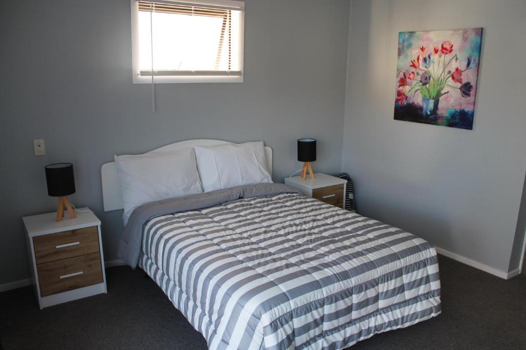 纳皮尔Aqua Apartment的一间卧室配有一张床,还有两个带两盏灯的床头柜
