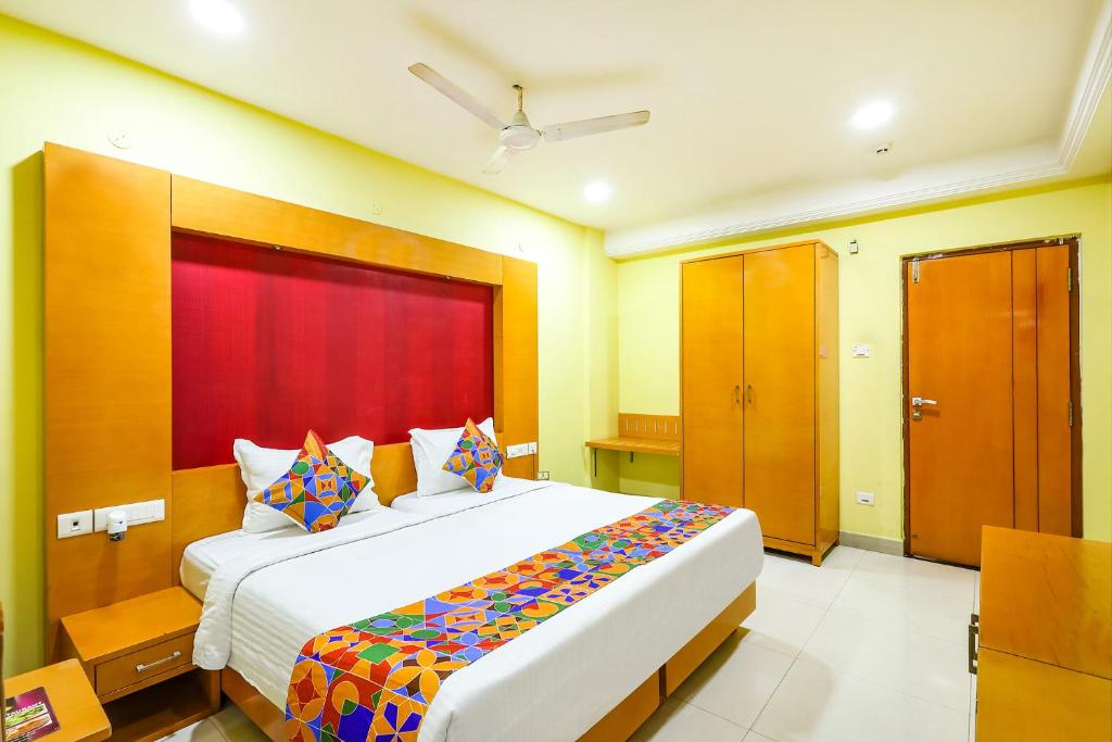 钦奈FabHotel Prime Mahalaya Residency的一间卧室配有一张大床和红色床头板