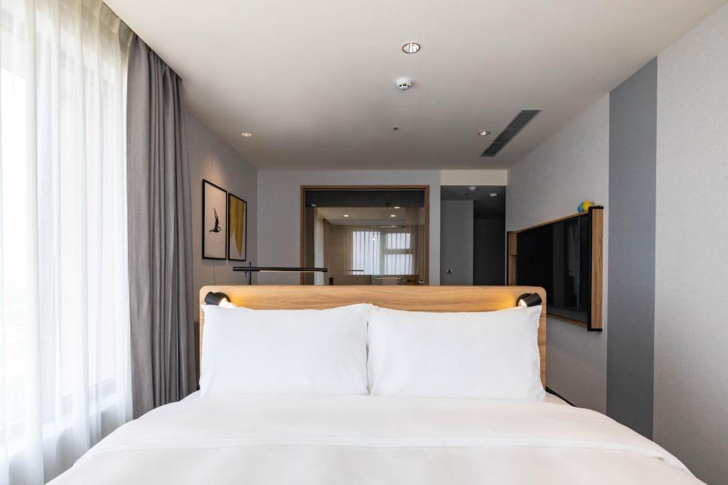 嘉义市voco Chiayi, an IHG Hotel的卧室配有白色的床铺和白色的枕头