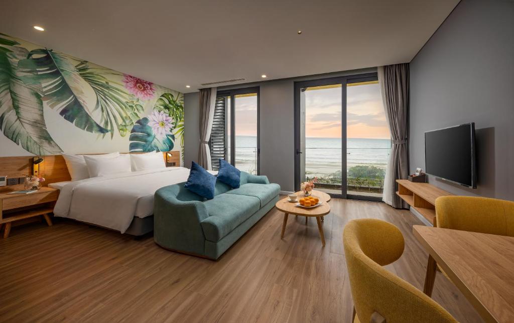 Nam KhêFlamingo Ibiza Hải Tiến的酒店客房配有床、沙发和电视。