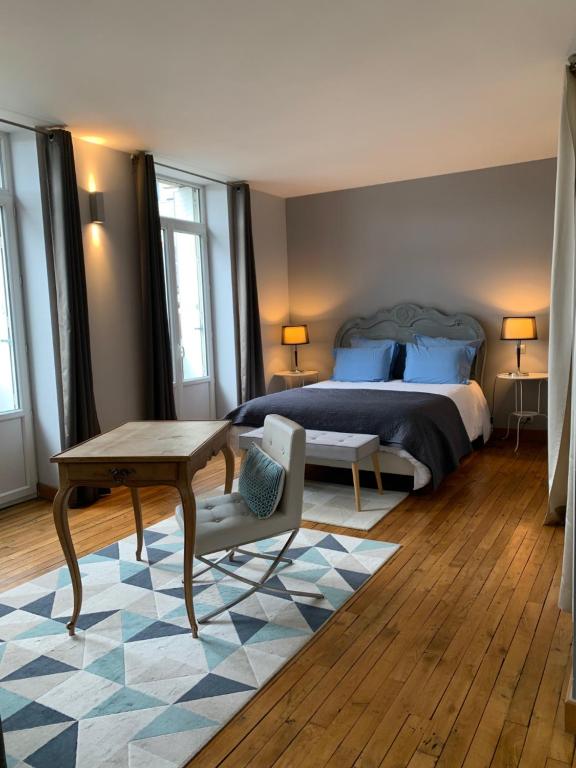 布里夫拉盖亚尔德Hôtel SPA Le Miel des Muses的一间卧室配有一张床、一张桌子和一张桌子