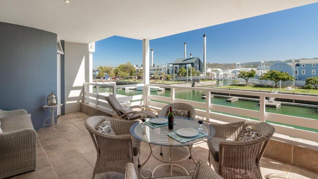 克尼斯纳Sunny Dry Mill Apartment on Thesen Islands的阳台配有桌椅,享有海港的景致。