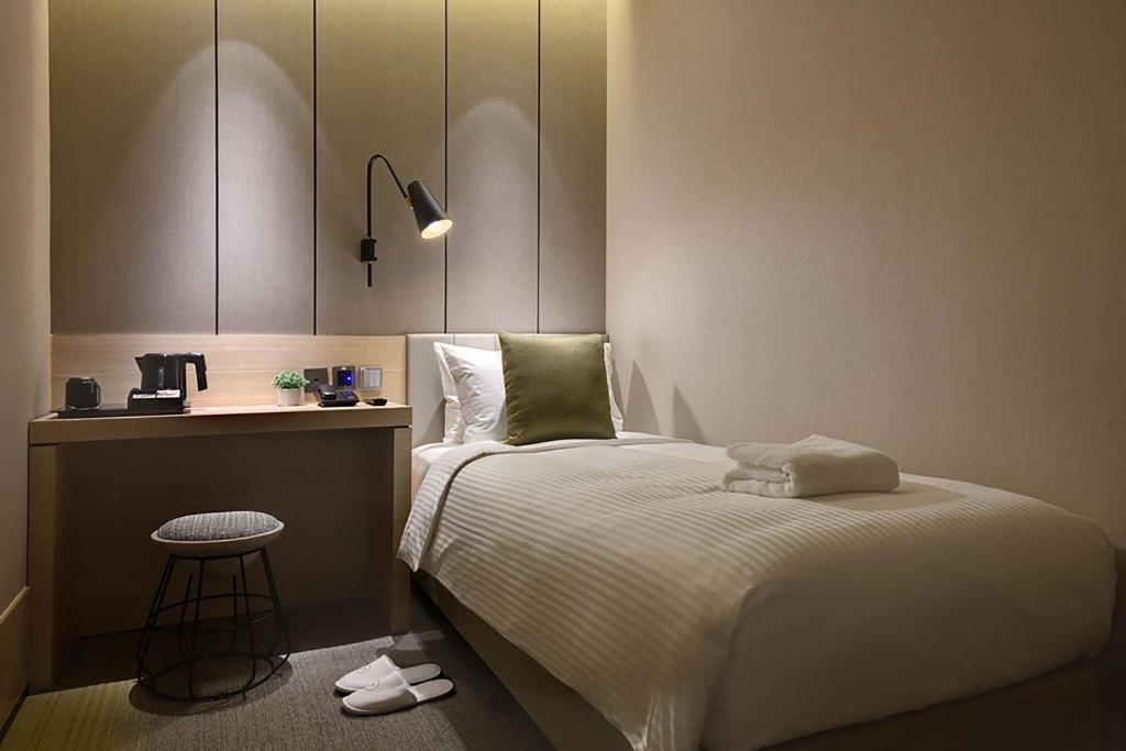 新加坡Aerotel Transit Hotel, Terminal 1 Airside的一间卧室配有床、桌子和凳子