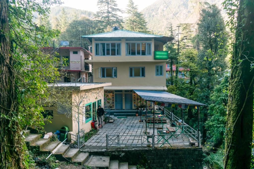 麦罗肯机Eevolve Dharamkot - An Eco Hostel的森林中间的山丘上的房子