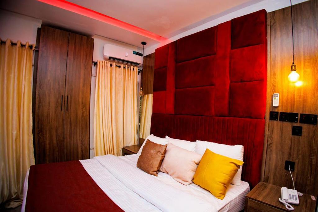 阿沙巴Vic & J Lounge and Hotel Asaba的一间卧室配有红色和黄色枕头的床