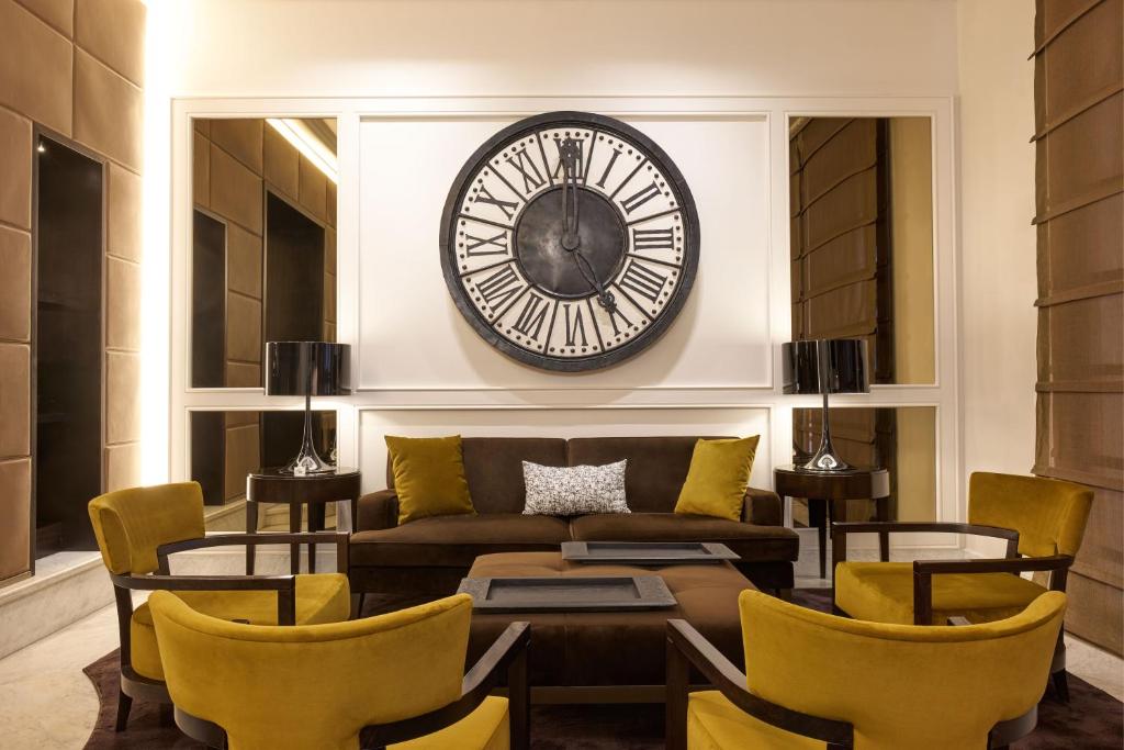 罗马马斯卡尼酒店的客厅配有沙发和墙上的时钟