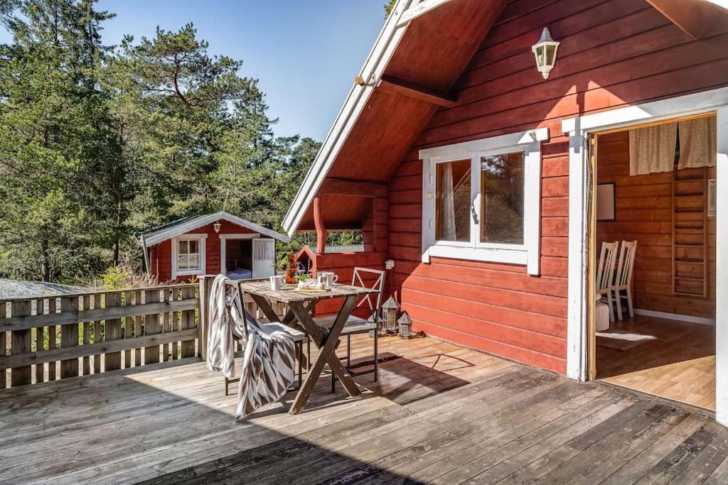DjurhamnCosy Cottages Close To Water的木制甲板上的红色小屋,配有桌子