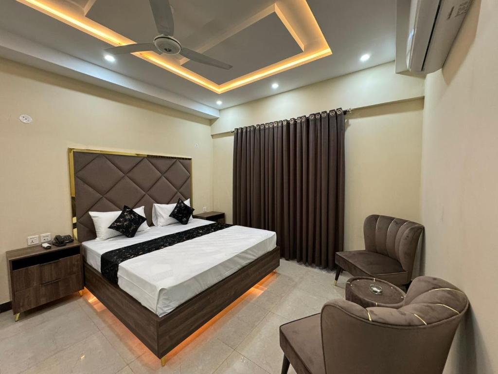 拉合尔Gold Pine Hotel Lahore的一间卧室配有一张床、一把椅子和一张沙发