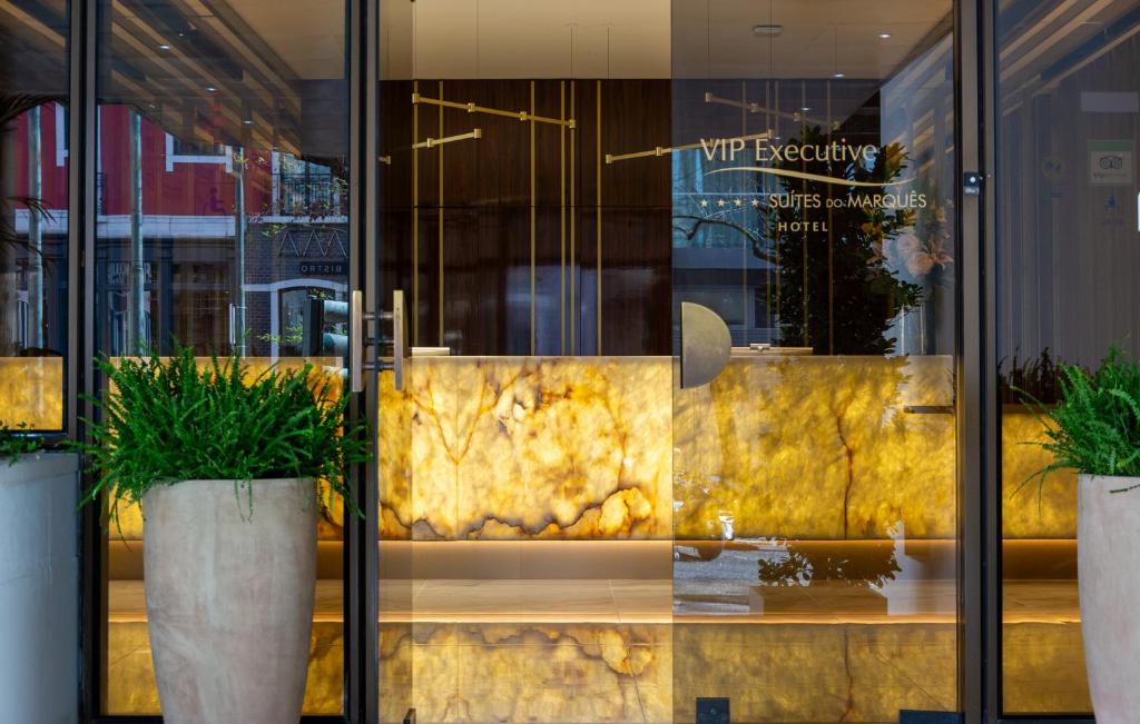 里斯本VIP Executive Suites do Marquês Hotel的前面有两盆植物的商店窗户