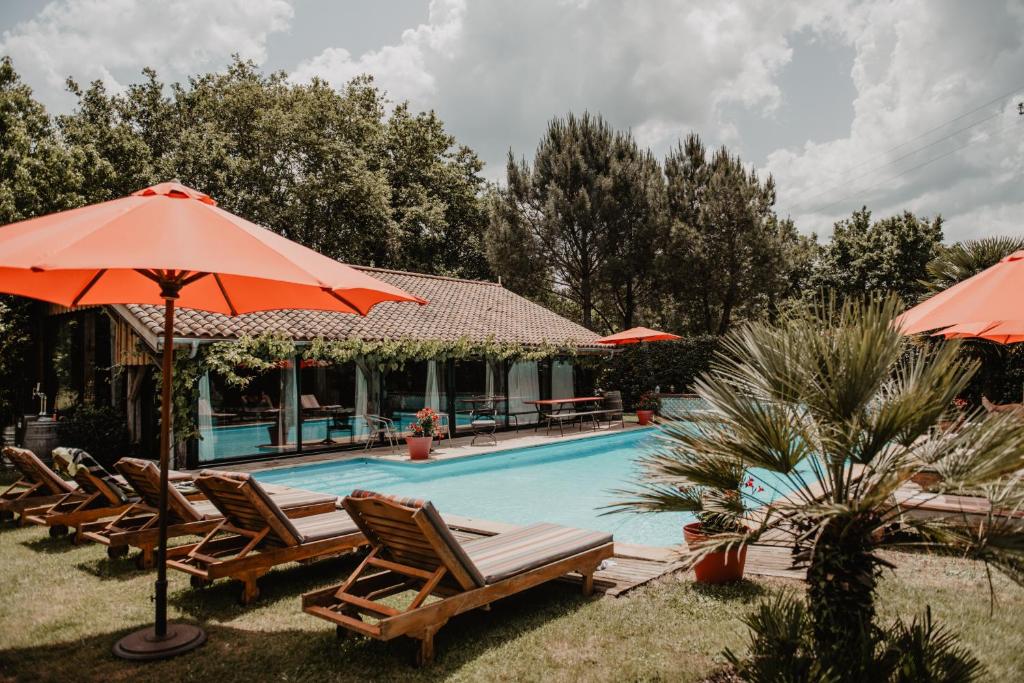 波讷地区圣朱利安Le Domaine de Petiosse的毗邻度假酒店的带椅子和遮阳伞的游泳池