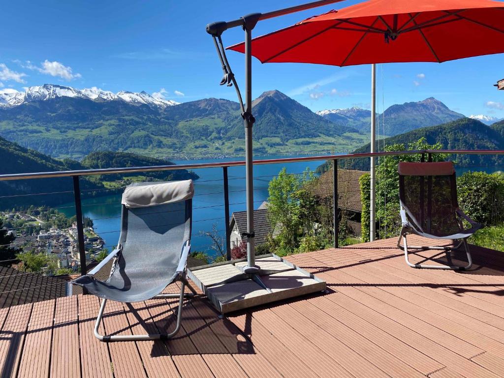 菲茨瑙Cozy House above Lake Lucerne in car-free Vitznau Mittlerschwanden at Mount Rigi railway的观景甲板上配有两把椅子和一把遮阳伞