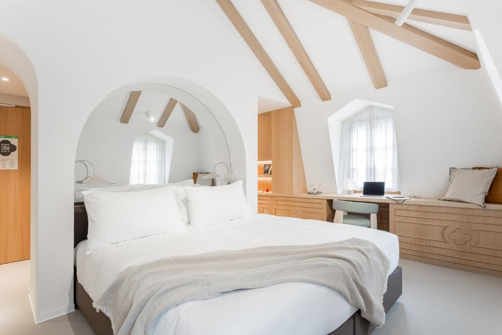 圣于尔萨讷Hôtel de La Cigogne的白色卧室配有一张大床和一张书桌