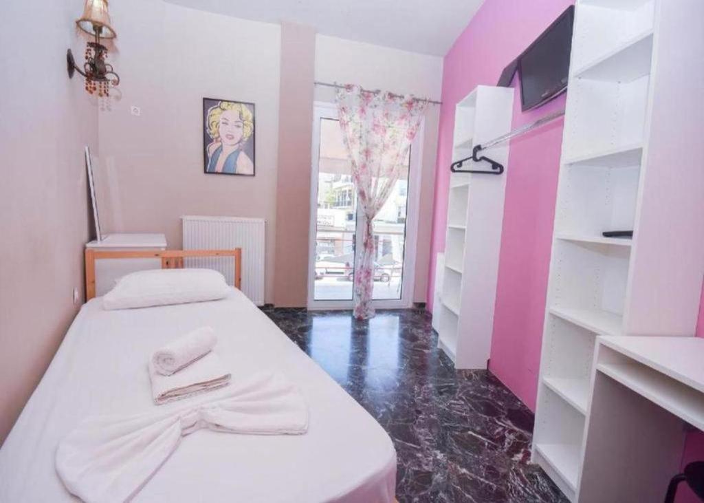 马科普隆Marilyn Athens Airport的小房间,设有一张床和粉红色的墙壁