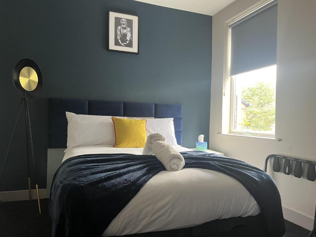 谢菲尔德Sleeps up to 8 A 4-Bed House all with en-suites的一间卧室配有一张蓝色墙壁的床和一扇窗户