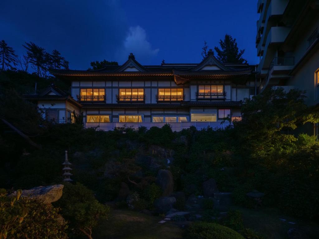 鹤冈市Kameya Hotel的夜晚的亚洲房屋,灯光照亮