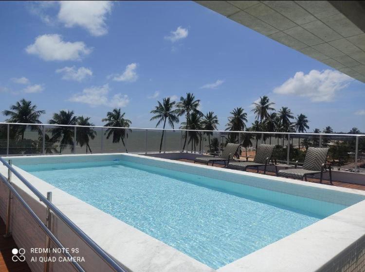 若昂佩索阿Apt beira-mar Cabo Branco的棕榈树建筑顶部的游泳池