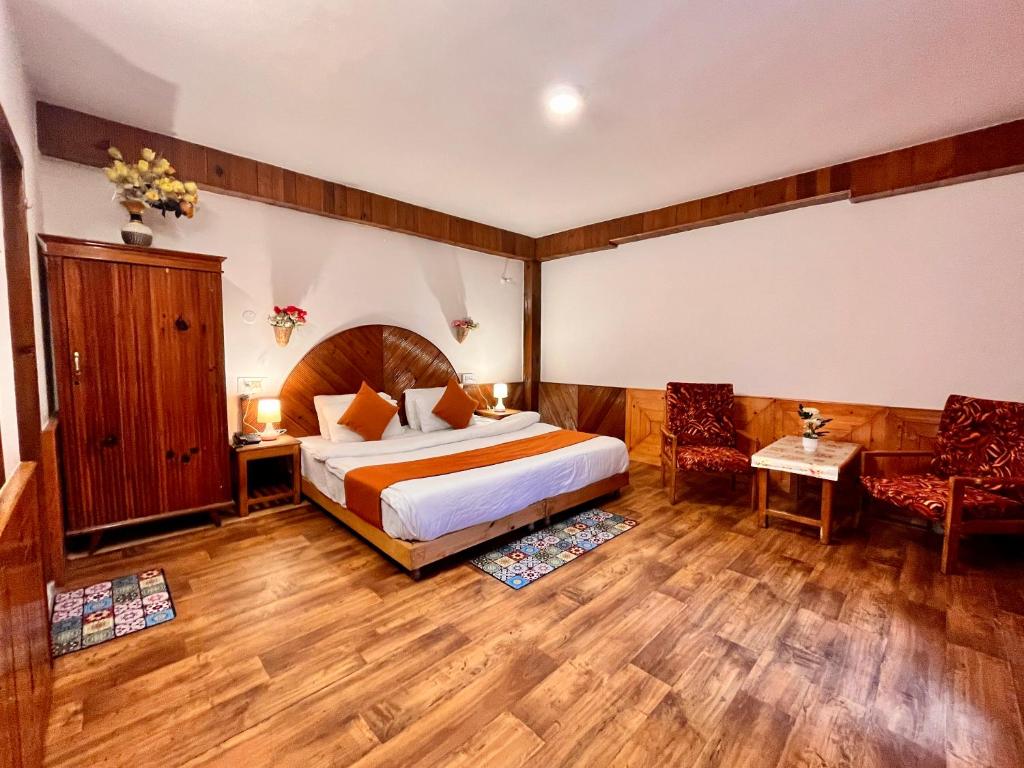 马拉里Ganga Cottage !! 1,2,3 bedrooms cottage available near mall road manali的酒店客房,配有一张床和两把椅子