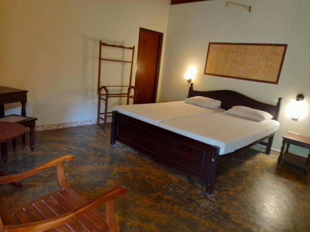 贝鲁沃勒Seetharama Garden of Life的一间卧室配有一张床、一把椅子和一张桌子
