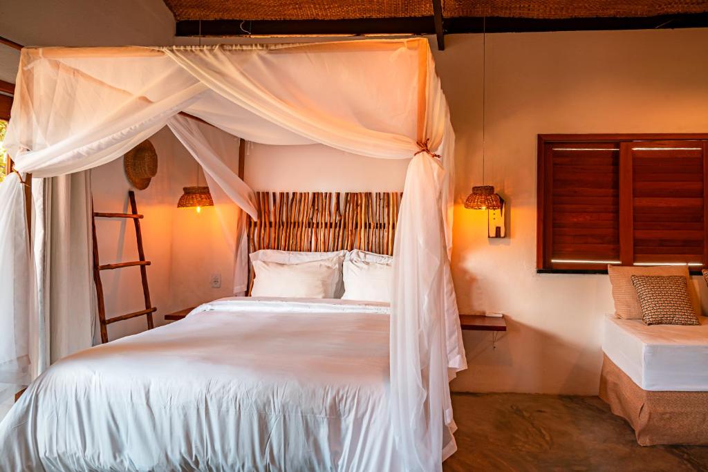 PacatubaPaka Bangalos, Pousada de Charme em Sergipe的卧室配有带白色床单和枕头的天蓬床。