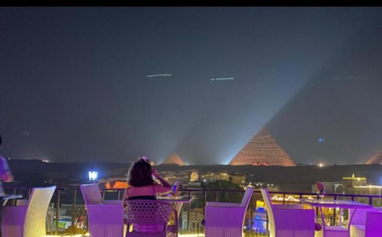 开罗Royal Golden Pyramids Inn的坐在紫色椅子上看着金字塔的女人