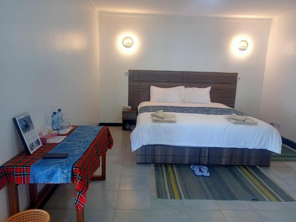 奈瓦沙Elsamere Lodge Naivasha的一间卧室配有一张大床和一张桌子