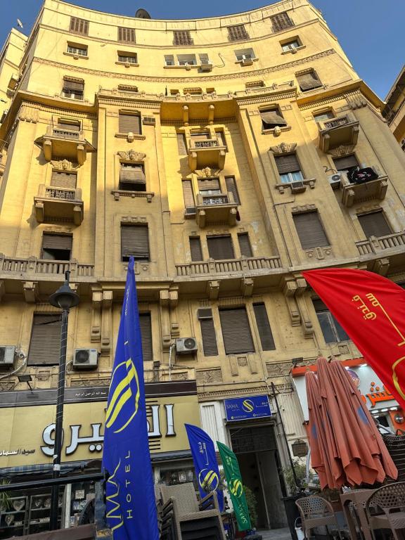 开罗Sama hotel的前面有旗帜的黄色建筑