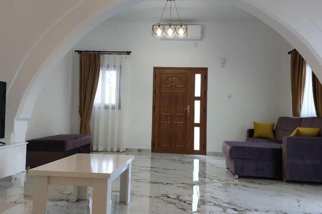 凯里尼亚Girne, Lapta'da Deniz ve Dağ Manzaralı的客厅配有两张紫色沙发和一张桌子