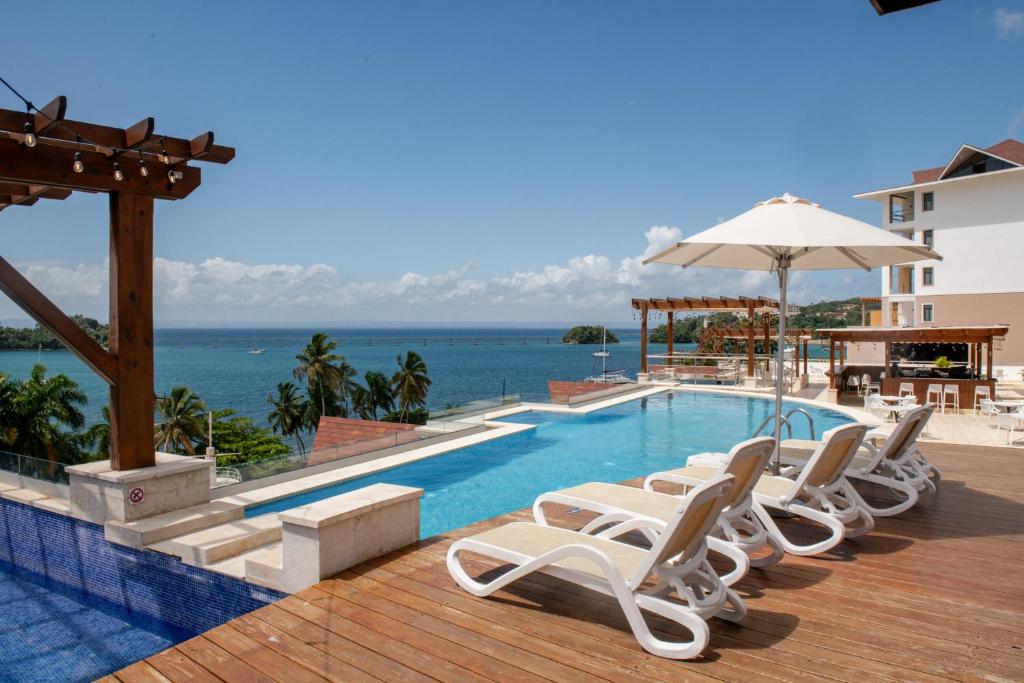 圣塔芭芭拉-山美纳Hacienda Samana Bay Hotel的一个带椅子和遮阳伞的游泳池以及大海