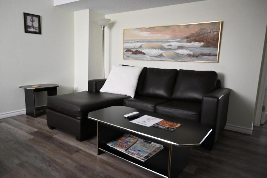 尼亚加拉瀑布Metropolitan Suite的客厅配有黑色真皮沙发和桌子