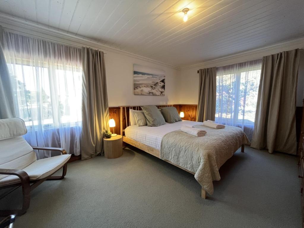 比舍诺Seaview Apartment - Tidelines of Bicheno的一间卧室配有一张床、一把椅子和窗户。