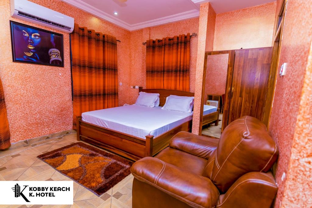 库马西Kobby Keach K Hotel的一间卧室配有一张床和一张皮椅