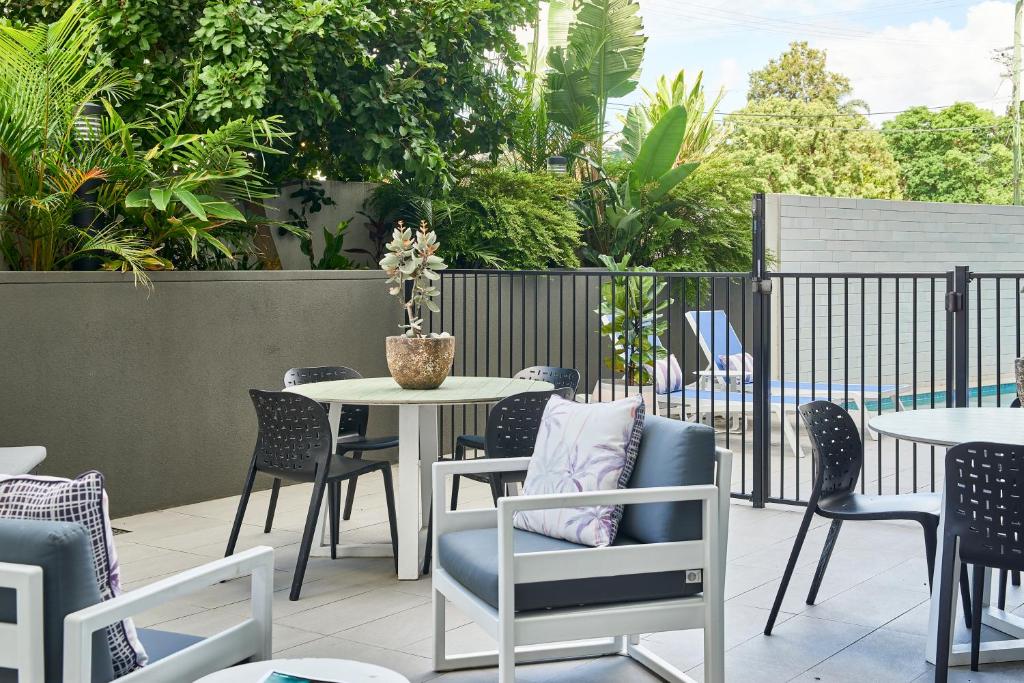 布里斯班奎斯特加农山公寓的庭院配有桌椅和桌椅。