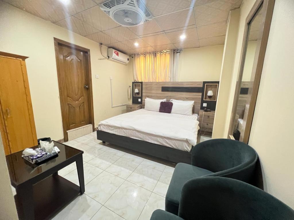伊斯兰堡Islamabad Premium Hotel的卧室配有一张床和一张桌子及椅子