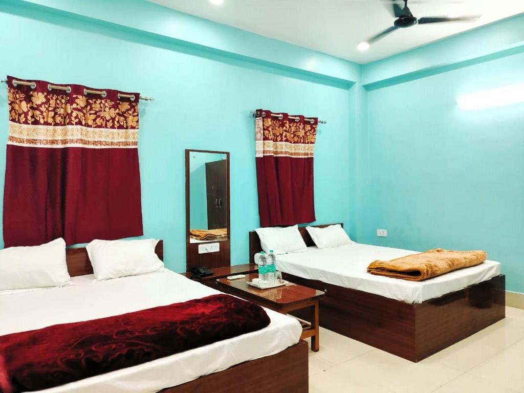 德奥加尔Hotel Ambika的配有两张床铺的蓝色墙壁和红色窗帘