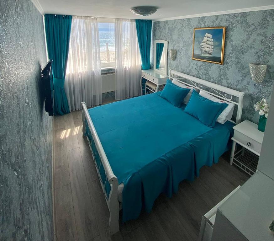 敖德萨萨兰达酒店的一间卧室配有蓝色的床和蓝色窗帘