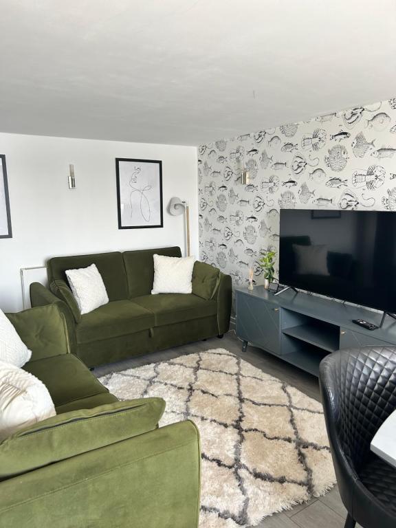 浦耳Sea view apartment on Poole Quay overlooking Sandbanks的客厅配有绿色沙发和平面电视