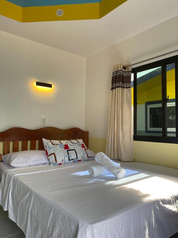 锡基霍尔Residencia Gemma的一间卧室配有一张带白色床单的床和一扇窗户。