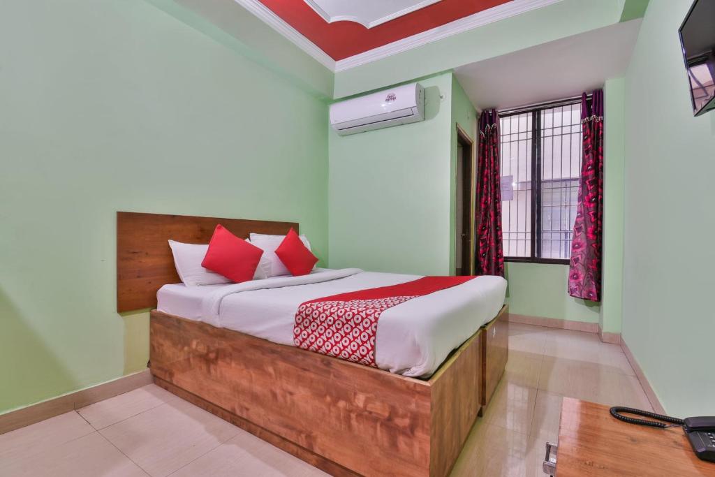 DīghaOYO Hotel Happy Journey的一间卧室配有一张带红色枕头的大床