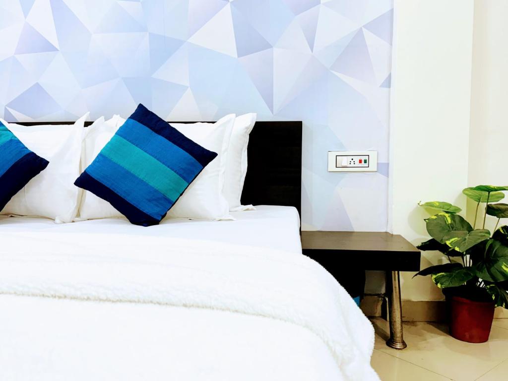 阿姆利则背包客之家旅馆的一间卧室配有白色床和蓝色枕头