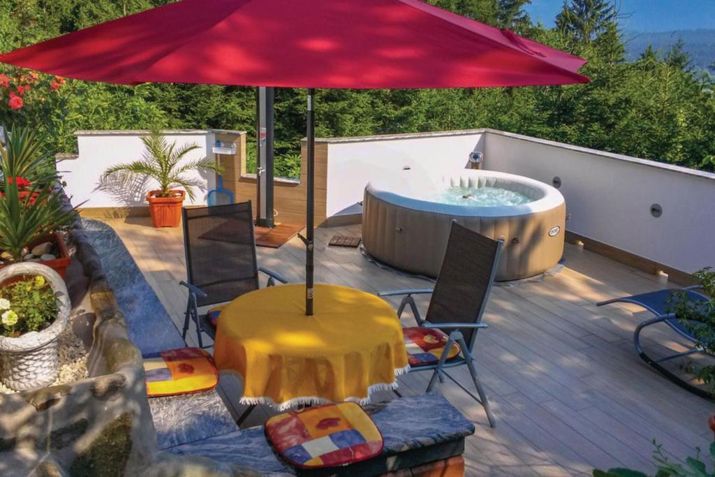 LjubnoBonidesa House With Whirlpool的一个带热水浴缸和红色遮阳伞的庭院