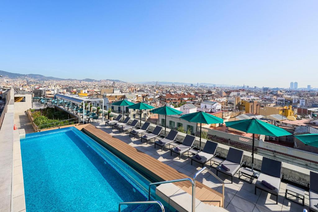 巴塞罗那InterContinental Barcelona, an IHG Hotel的一座带椅子和遮阳伞的大楼的顶部游泳池