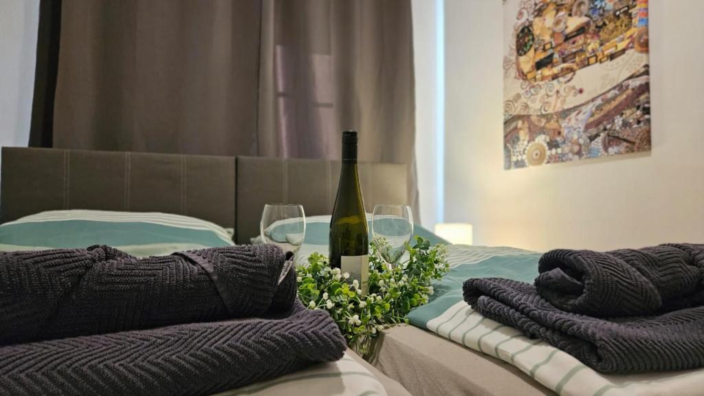 圣珀尔滕APARTMENTS RATZERSDORFER SEEN in 3100 SANKT PÖLTEN的一张带一瓶葡萄酒和两杯酒的床